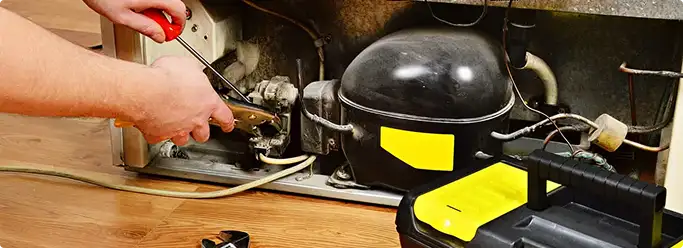 Refrigerator repair technician fixing the compressor and wiring in Fox Valley, IL