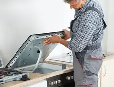 Appliance repair technician installing a built-in cooktop in Naperville, IL