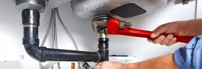 Garbage disposal repair technician tightening the sink drain and disposal connection in Naperville, IL