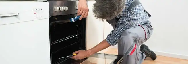 Oven repair technician inspecting and servicing an electric oven in Naperville, IL