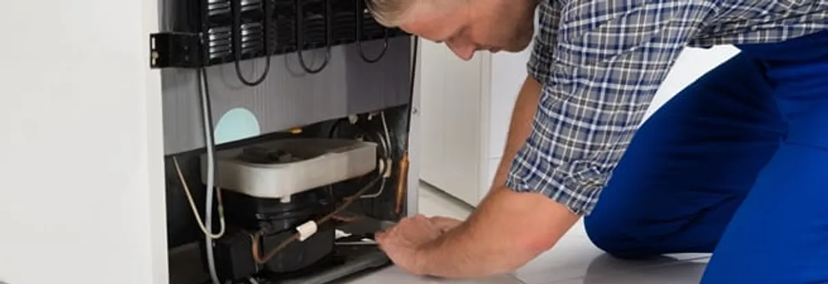 Refrigerator repair technician servicing the compressor and condenser area in Naperville, IL