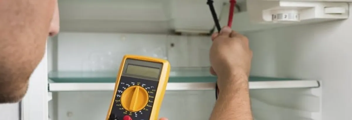 Refrigerator repair technician testing electrical components with a multimeter in Naperville, IL