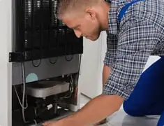 Refrigerator repair technician servicing the compressor and condenser area in Naperville, IL