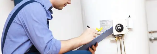 Water heater repair technician inspecting the unit and recording service notes in Naperville, IL