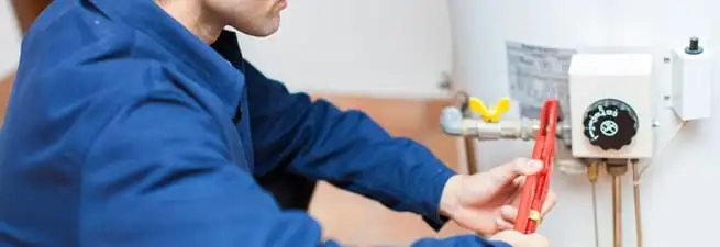 Water heater repair technician adjusting the temperature control and gas valve in Naperville, IL